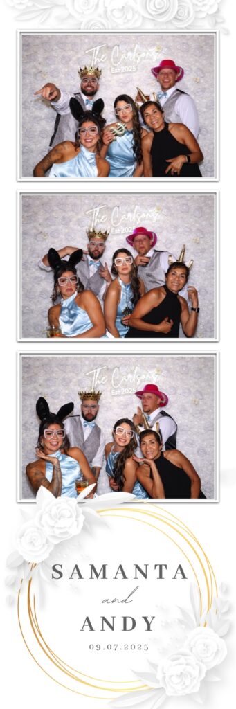 Wedding guests pose in front of a white rose wall for a photo booth rental at Sanctuary Golf Course in Sedalia Colorado.