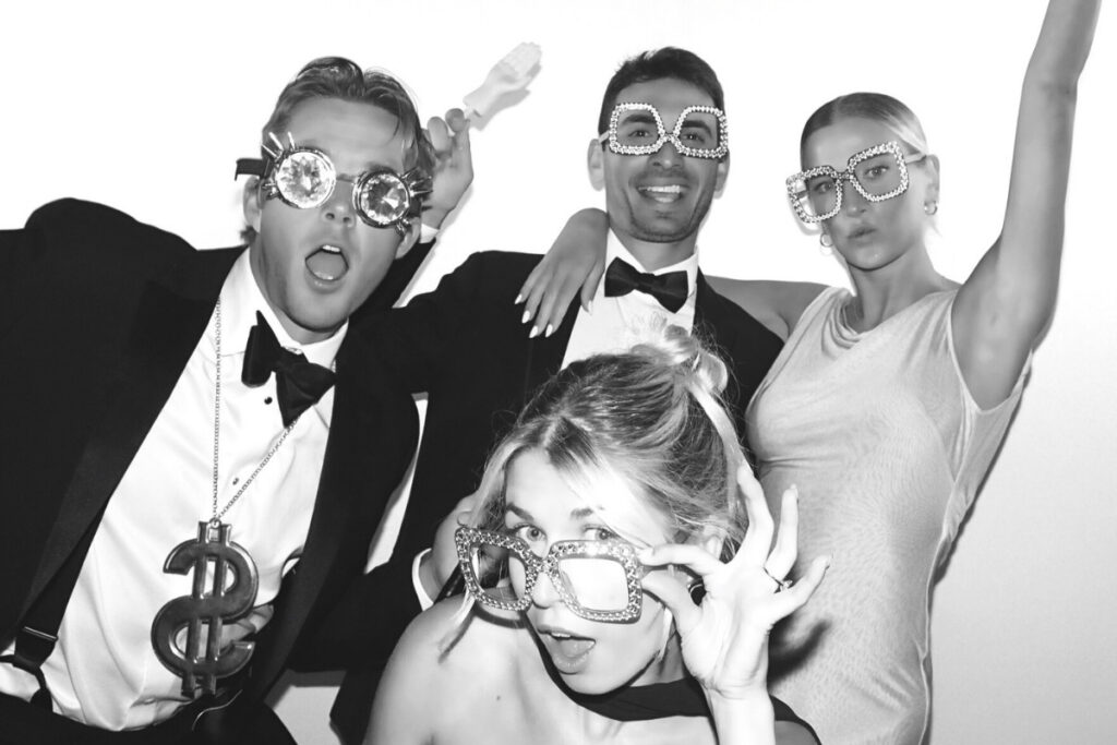 Guests pose in a black and white hollywood glam photo booth at an elevated wedding.