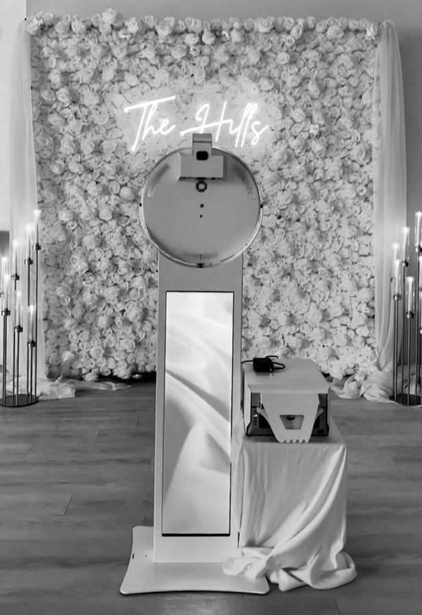 Photo booth rental setup with white rose wall at The Oaks at Plum Creek for a wedding.