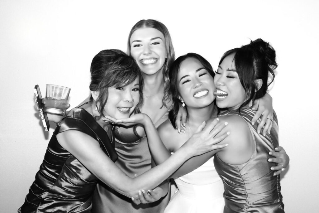 A group of wedding guests posing for a Hollywood glam photo booth with professional skin smoothing filters and a clean white backdrop